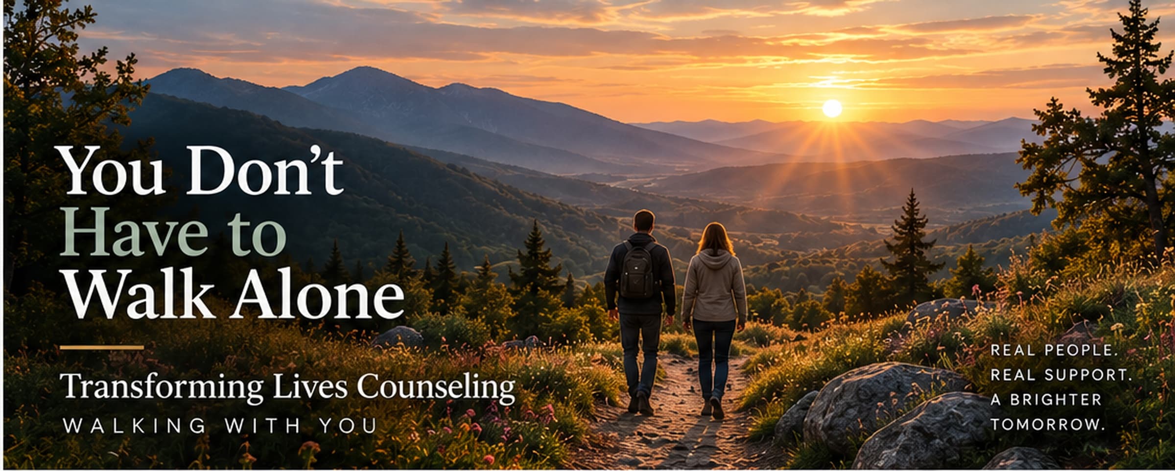 Two people walking toward a sunset in the mountains